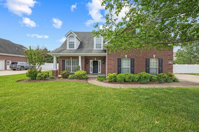 new england style home featuring fence, brick siding, and a front yard