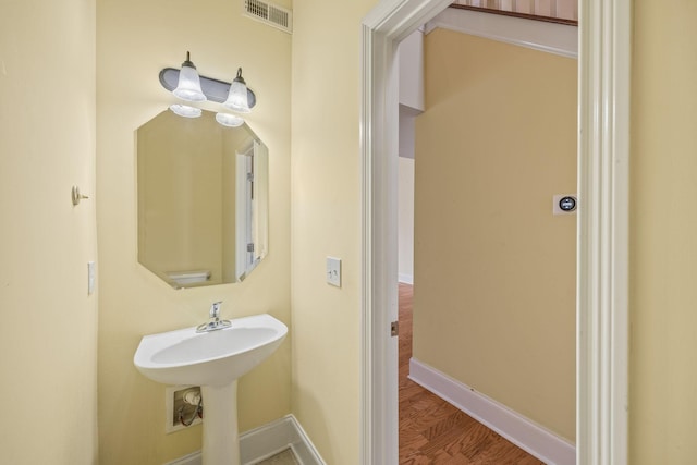 bathroom with a sink, baseboards, wood finished floors, and visible vents