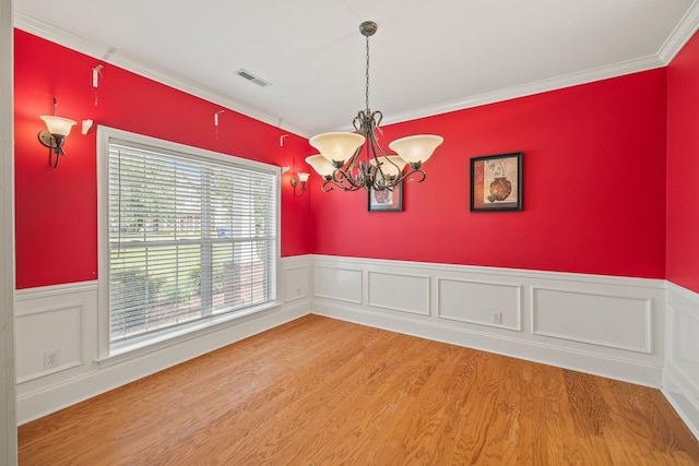 spare room featuring wainscoting, ornamental molding, a notable chandelier, and visible vents