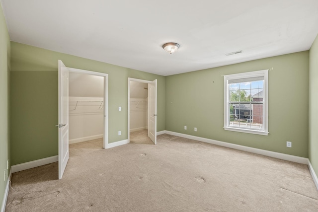 unfurnished bedroom featuring carpet flooring, baseboards, visible vents, and multiple closets