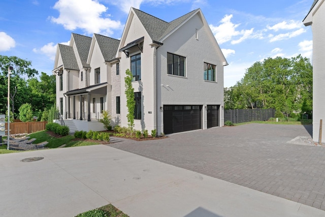 view of side of property with an attached garage, decorative driveway, and fence