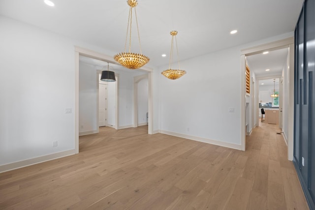 spare room featuring light wood-type flooring, recessed lighting, arched walkways, and baseboards