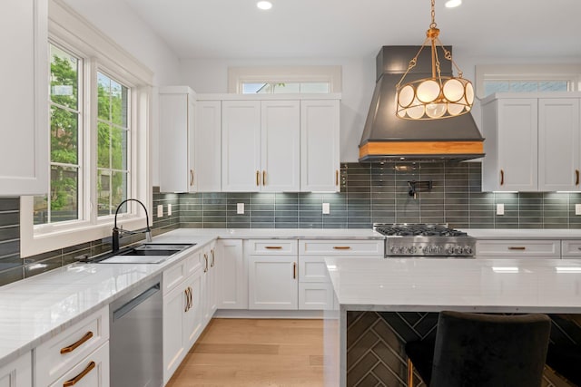 kitchen with a sink, appliances with stainless steel finishes, custom exhaust hood, white cabinetry, and light stone counters