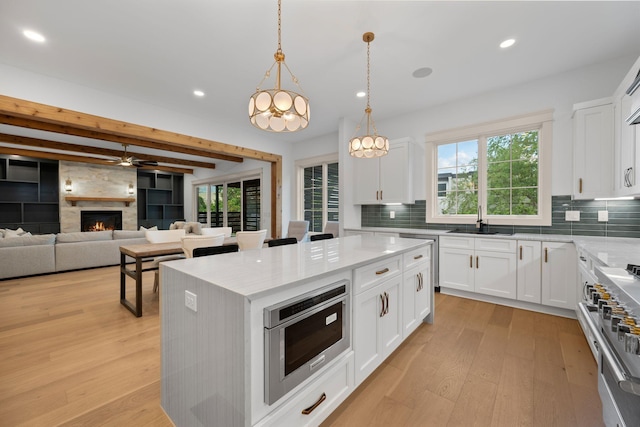 kitchen featuring a sink, light wood-style flooring, recessed lighting, high end stove, and decorative backsplash