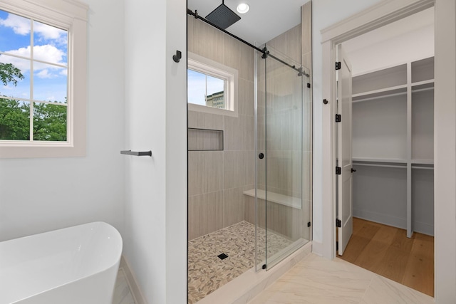 bathroom with a stall shower, a walk in closet, a freestanding tub, baseboards, and recessed lighting