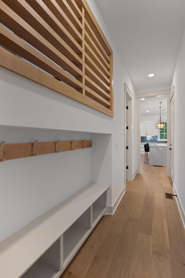 hall featuring light wood-type flooring, recessed lighting, a chandelier, and baseboards