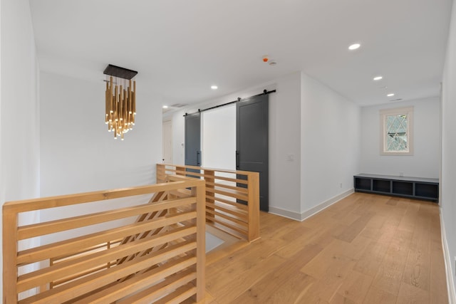 hall featuring a barn door, an upstairs landing, light wood-style flooring, recessed lighting, and baseboards