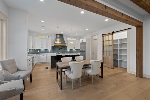 dining room with a barn door, light wood-type flooring, recessed lighting, and baseboards