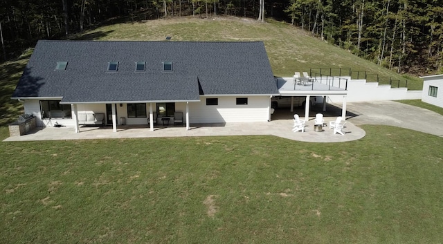 back of property featuring a lawn, a patio, and a shingled roof