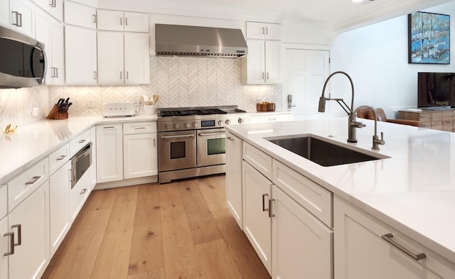 kitchen featuring light countertops, extractor fan, appliances with stainless steel finishes, and a sink