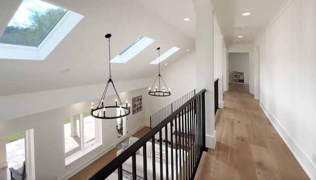 corridor with light wood-style floors, baseboards, recessed lighting, a chandelier, and vaulted ceiling with skylight
