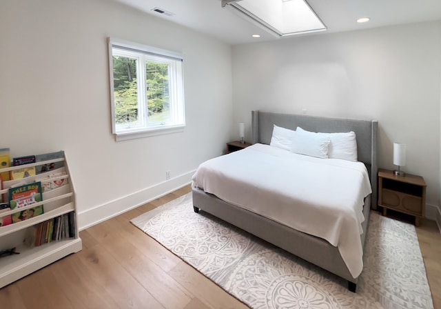 bedroom with a skylight, recessed lighting, wood finished floors, and visible vents