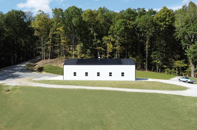 view of home's community featuring a lawn, a forest view, a pole building, and an outbuilding