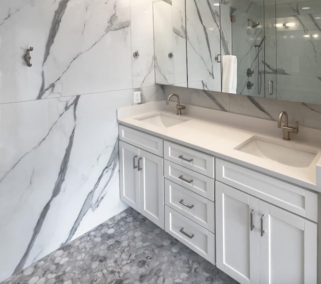 full bathroom featuring double vanity, a sink, and a marble finish shower