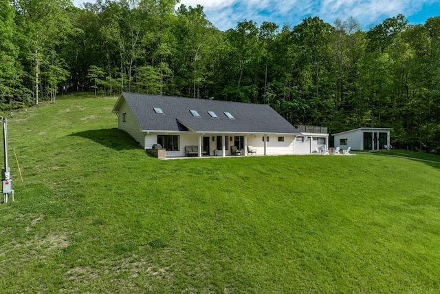 rear view of house featuring a yard, a forest view, and a patio area