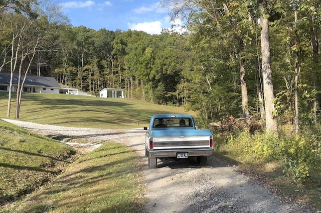 view of road with driveway and a wooded view