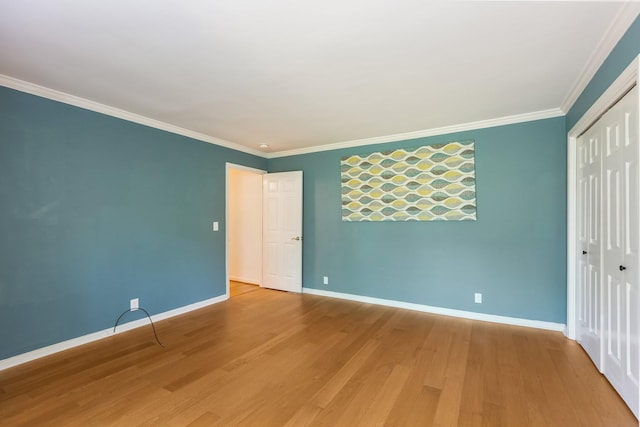 unfurnished bedroom featuring crown molding, baseboards, wood finished floors, and a closet