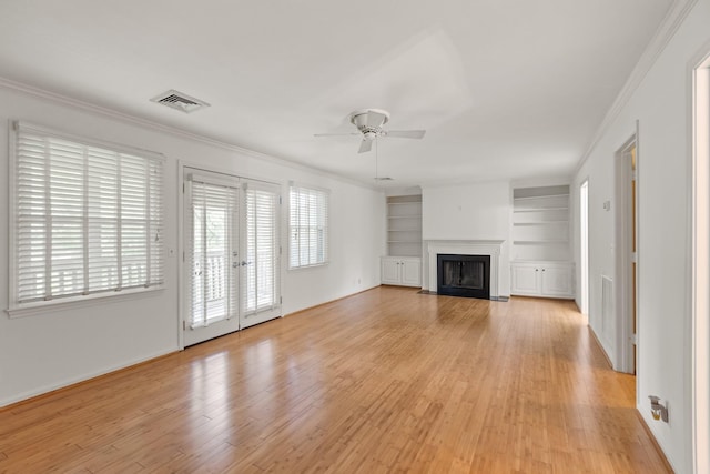 unfurnished living room featuring light wood-style floors, built in features, a ceiling fan, a fireplace with flush hearth, and visible vents