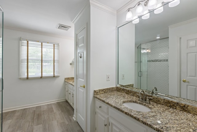 full bathroom with vanity, a shower stall, wood finished floors, visible vents, and ornamental molding