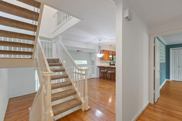 stairway featuring baseboards, ornamental molding, and wood finished floors