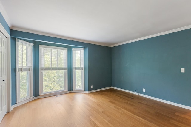 empty room featuring crown molding, baseboards, and wood finished floors
