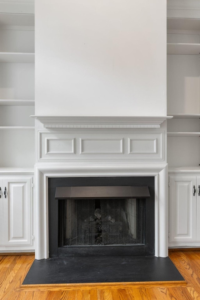 interior details featuring a fireplace with flush hearth and wood finished floors