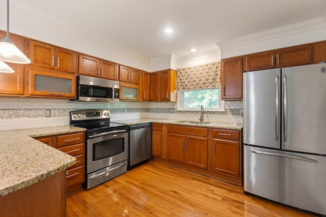 kitchen with crown molding, appliances with stainless steel finishes, a sink, brown cabinetry, and decorative backsplash