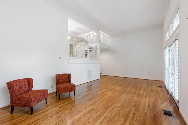 living area featuring stairway, light wood-style floors, and visible vents