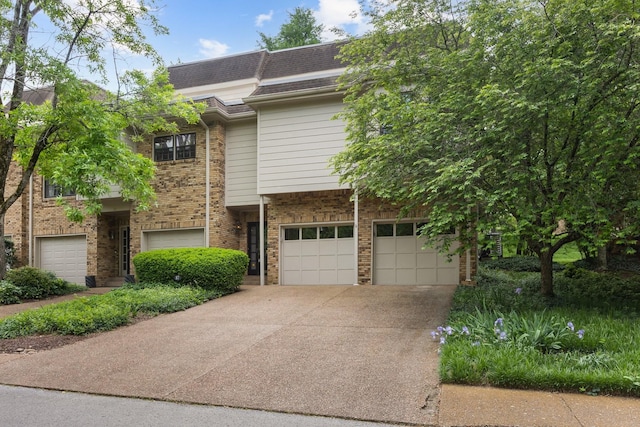 townhome / multi-family property with an attached garage, a shingled roof, brick siding, and concrete driveway