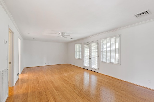 spare room with crown molding, a ceiling fan, visible vents, and light wood finished floors