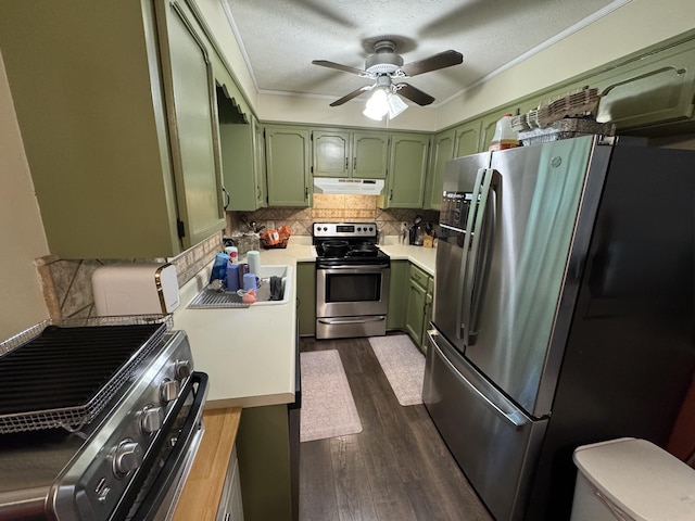 kitchen with dark wood-style flooring, light countertops, under cabinet range hood, appliances with stainless steel finishes, and green cabinets