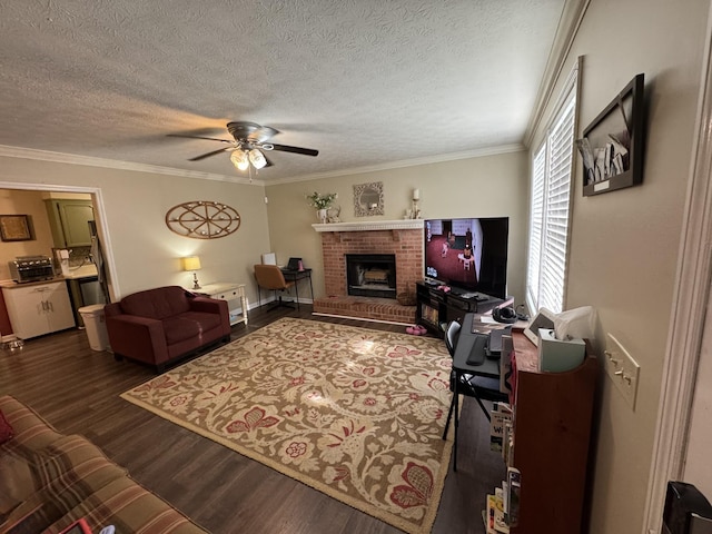 living area with ceiling fan, a fireplace, a textured ceiling, dark wood-type flooring, and ornamental molding