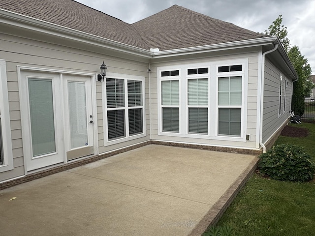 exterior space featuring a patio and roof with shingles