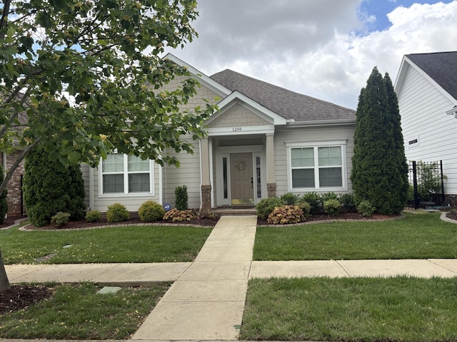 view of front of house featuring a shingled roof and a front yard