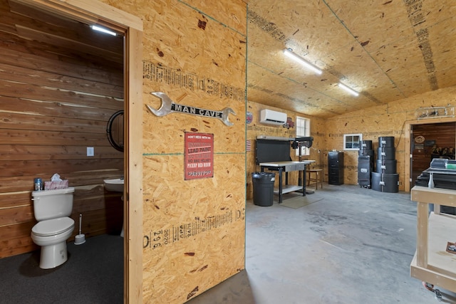 misc room featuring wood walls, concrete flooring, and a wall unit AC