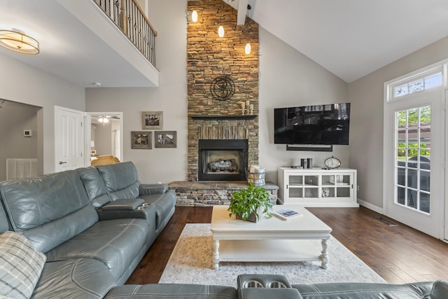 living area featuring visible vents, dark wood-style flooring, baseboards, a stone fireplace, and high vaulted ceiling