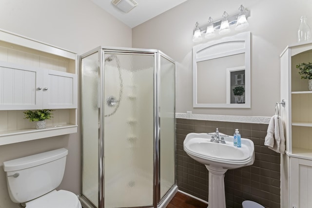 full bathroom with tile walls, a shower stall, toilet, and visible vents