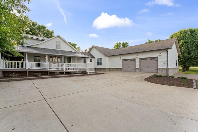 farmhouse inspired home featuring covered porch, driveway, and a garage