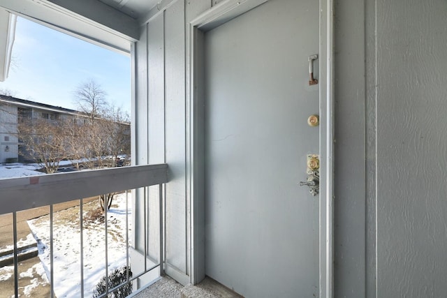 snow covered property entrance featuring a balcony