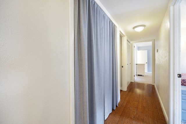 hall featuring baseboards and dark wood-style floors