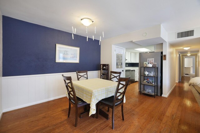 dining room with wainscoting, wood finished floors, and visible vents