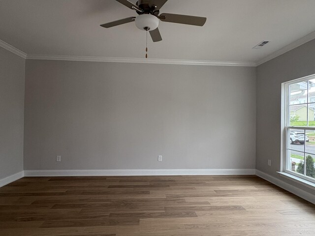 unfurnished room with wood finished floors, ornamental molding, visible vents, and a wealth of natural light