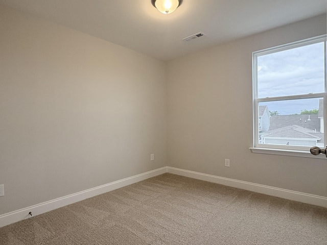 empty room with baseboards, light carpet, and visible vents