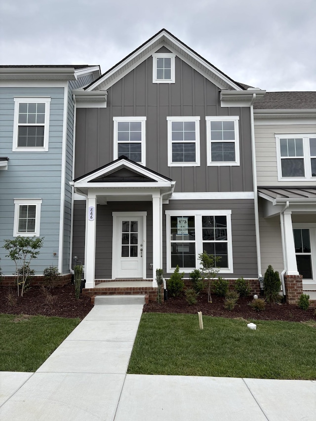 view of front facade with covered porch, board and batten siding, and a front lawn