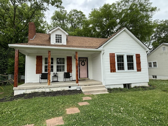 view of front facade with a porch, a chimney, roof with shingles, and a front lawn