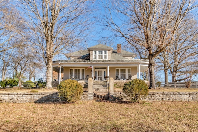 view of front of house featuring a porch, fence, a chimney, and stucco siding