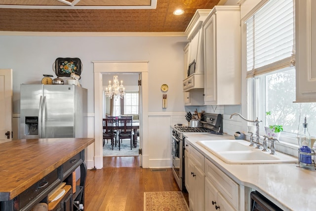 kitchen with appliances with stainless steel finishes, a sink, butcher block counters, a chandelier, and light wood-style floors
