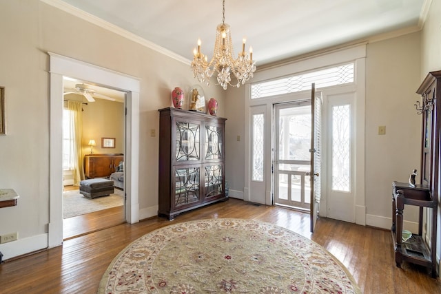 foyer entrance with wood-type flooring, baseboards, ornamental molding, and ceiling fan with notable chandelier