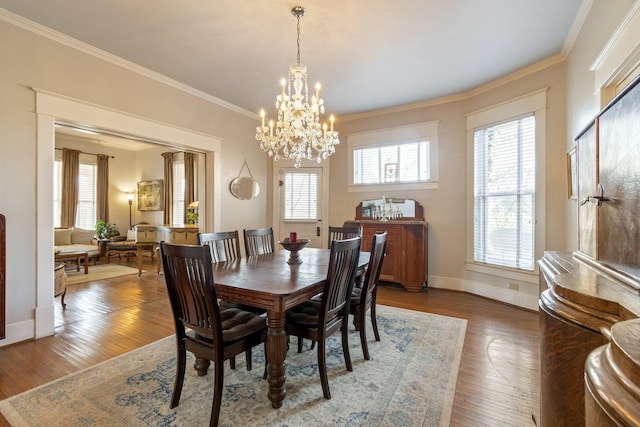 dining area featuring crown molding, a chandelier, a healthy amount of sunlight, and wood finished floors