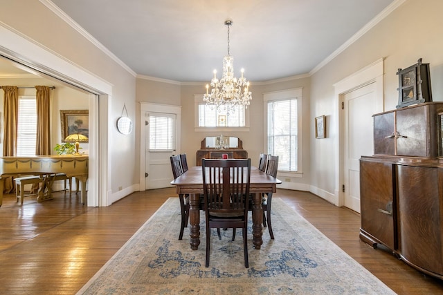 dining room featuring baseboards, ornamental molding, wood finished floors, and a chandelier